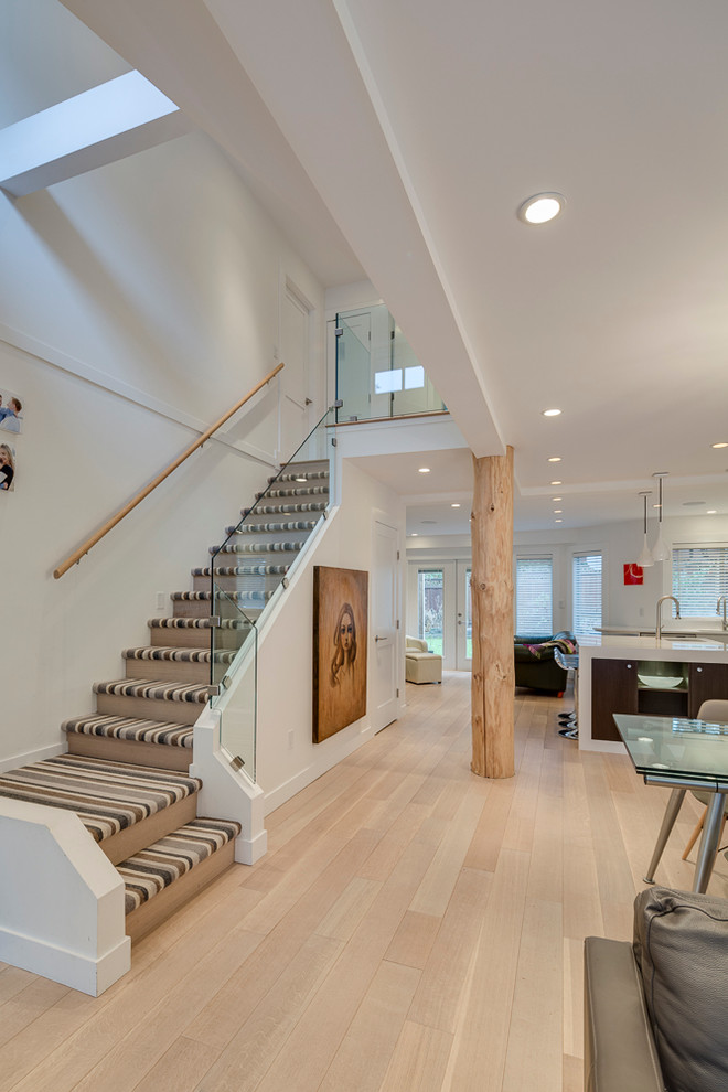 Mid-sized minimalist carpeted l-shaped glass railing staircase photo in Vancouver with wooden risers