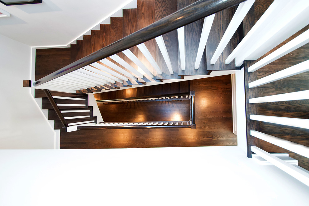 Réalisation d'un grand escalier design en U avec des marches en bois et des contremarches en bois.