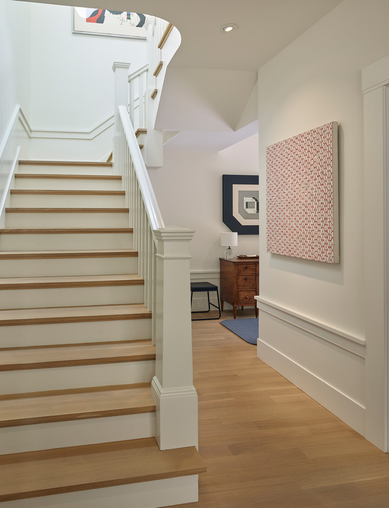 Imagen de escalera en U clásica de tamaño medio con escalones de madera, contrahuellas de madera pintada y barandilla de madera