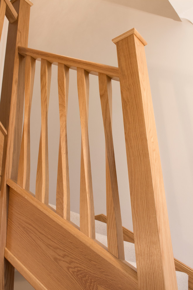 チェシャーにあるコンテンポラリースタイルのおしゃれなかね折れ階段 (カーペット張りの蹴込み板、木材の手すり) の写真