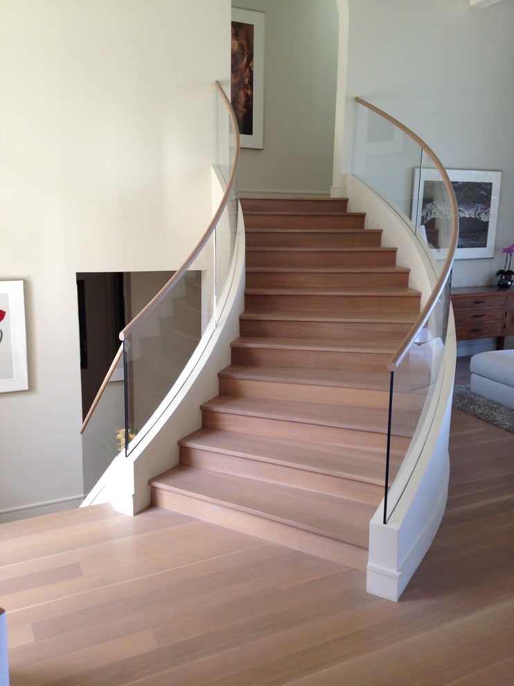 Пример оригинального дизайна: изогнутая деревянная лестница среднего размера в стиле модернизм с деревянными ступенями