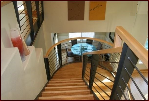 Staircase - large contemporary wooden curved metal railing staircase idea in Orange County with wooden risers