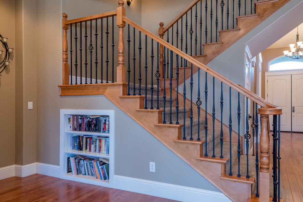 На фото: большая угловая деревянная лестница в классическом стиле с ступенями с ковровым покрытием и металлическими перилами