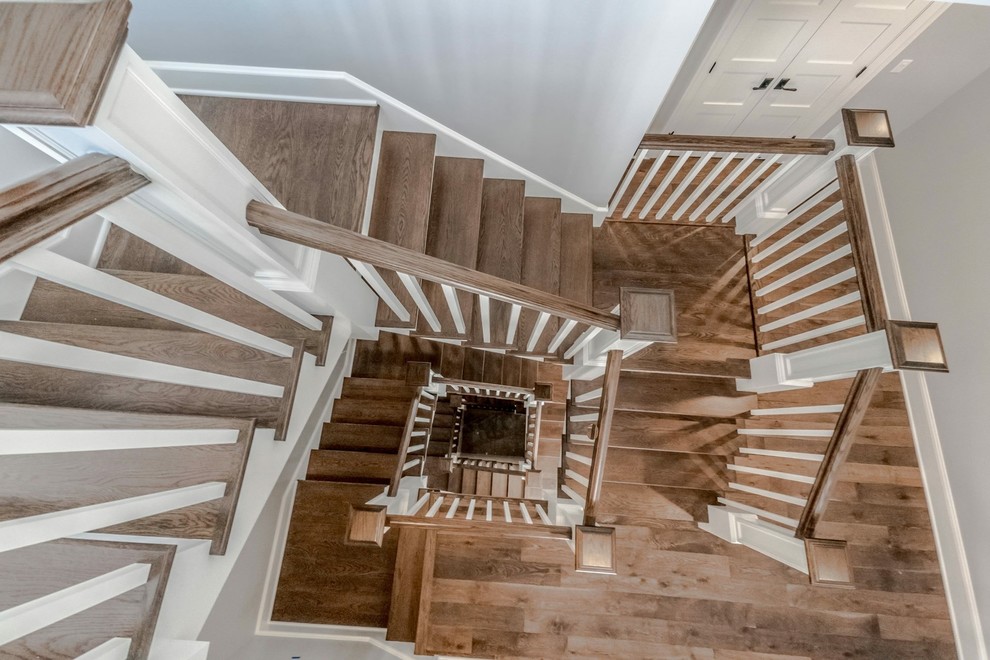Ejemplo de escalera suspendida clásica renovada grande con escalones de madera, contrahuellas de madera y barandilla de madera