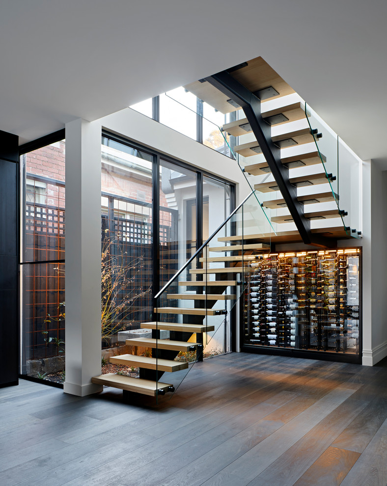 Aménagement d'un escalier sans contremarche contemporain en U avec des marches en bois, un garde-corps en verre et éclairage.