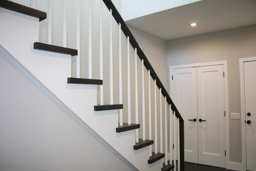 На фото: угловая лестница среднего размера в стиле неоклассика (современная классика) с деревянными ступенями, крашенными деревянными подступенками и деревянными перилами с