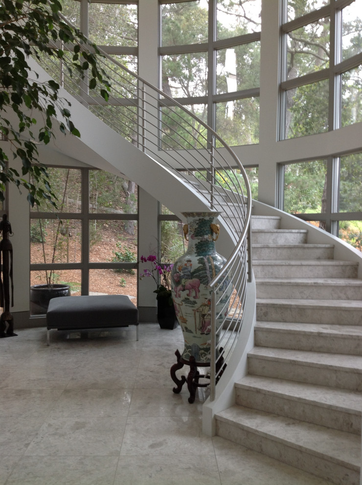 Exemple d'un très grand escalier courbe éclectique en marbre avec des contremarches en marbre et un garde-corps en métal.