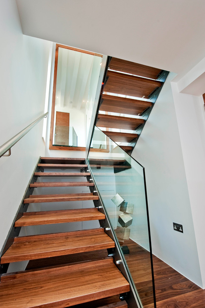 Idée de décoration pour un escalier minimaliste avec un garde-corps en verre et palier.