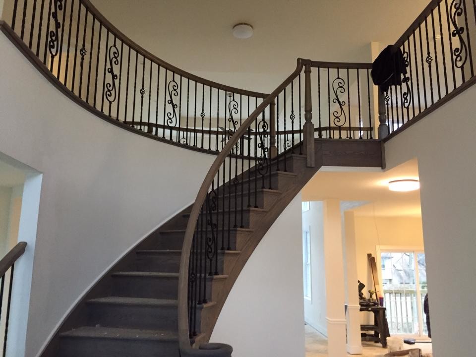 Large elegant wooden curved staircase photo in Philadelphia with wooden risers