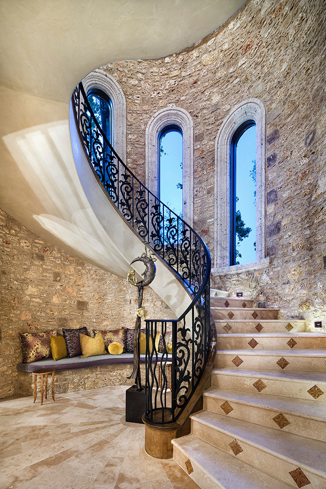 Large mediterranean curved metal railing staircase in Houston with marble treads and marble risers.