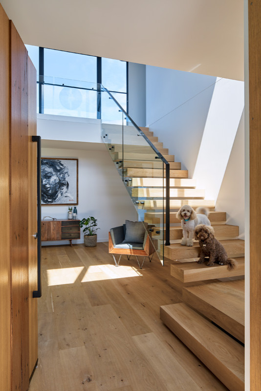 Diseño de escalera suspendida contemporánea extra grande con escalones de madera, contrahuellas de madera y barandilla de vidrio