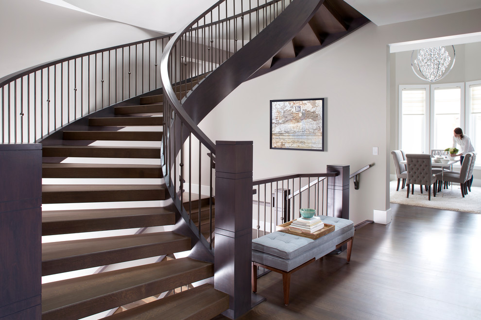 Стильный дизайн: большая изогнутая лестница в стиле неоклассика (современная классика) с деревянными ступенями без подступенок - последний тренд