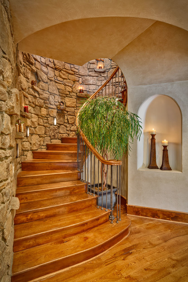 Large rustic wood curved staircase in Other with wood risers.
