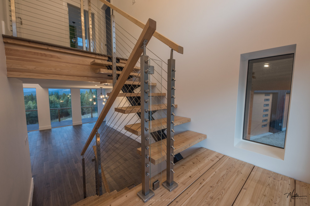 This is an example of a medium sized urban wood u-shaped wire cable railing staircase in Vancouver with open risers.