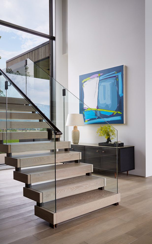 Design ideas for a contemporary wood glass railing staircase in Denver with open risers and feature lighting.