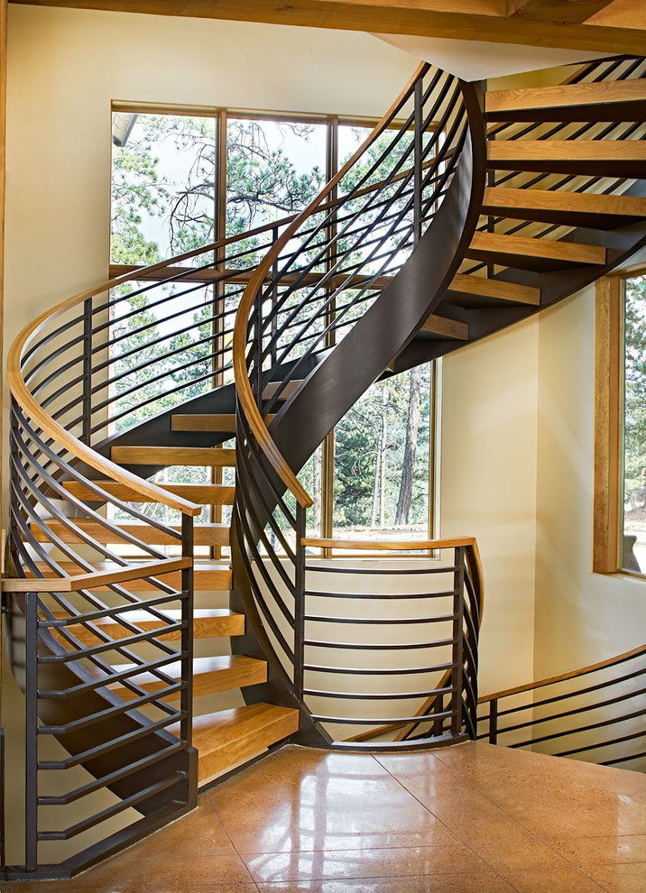 Modelo de escalera curva rural grande con escalones de madera, contrahuellas de madera y barandilla de metal