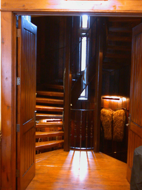 На фото: большая винтовая лестница в стиле кантри с деревянными ступенями с