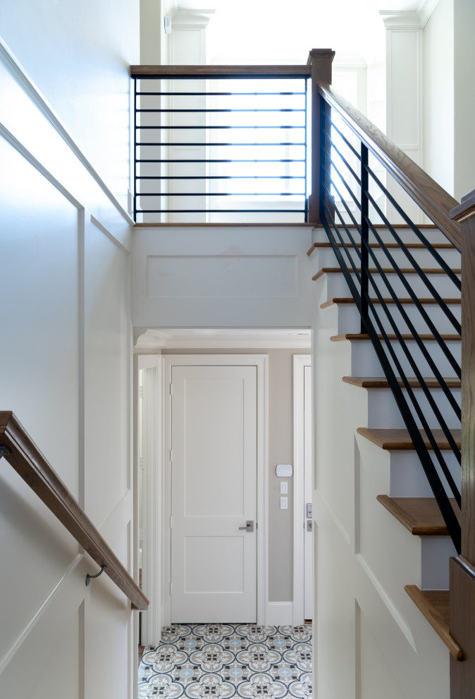 На фото: угловая деревянная лестница в стиле неоклассика (современная классика) с деревянными ступенями, металлическими перилами и панелями на стенах