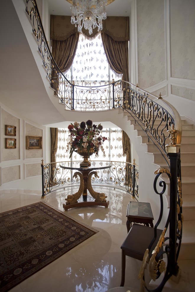 Cette photo montre un très grand escalier courbe victorien en marbre avec des contremarches en marbre et un garde-corps en métal.