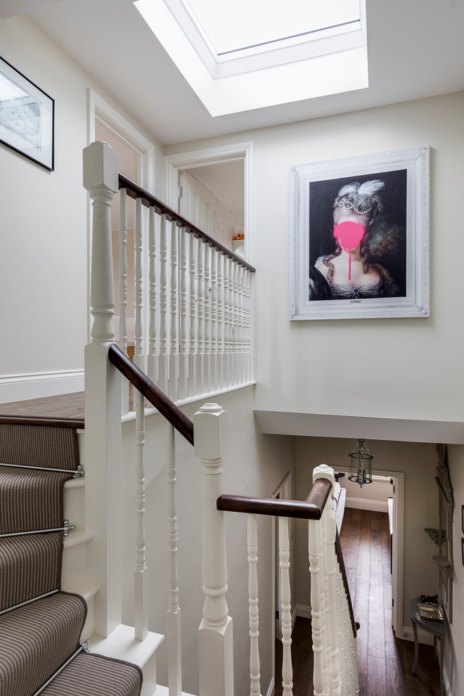 Photo of a medium sized classic carpeted l-shaped wood railing staircase in London with carpeted risers.