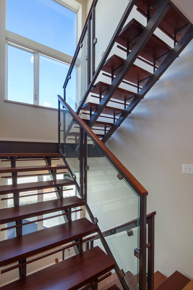 Стильный дизайн: большая п-образная лестница в стиле модернизм с деревянными ступенями и стеклянными перилами без подступенок - последний тренд