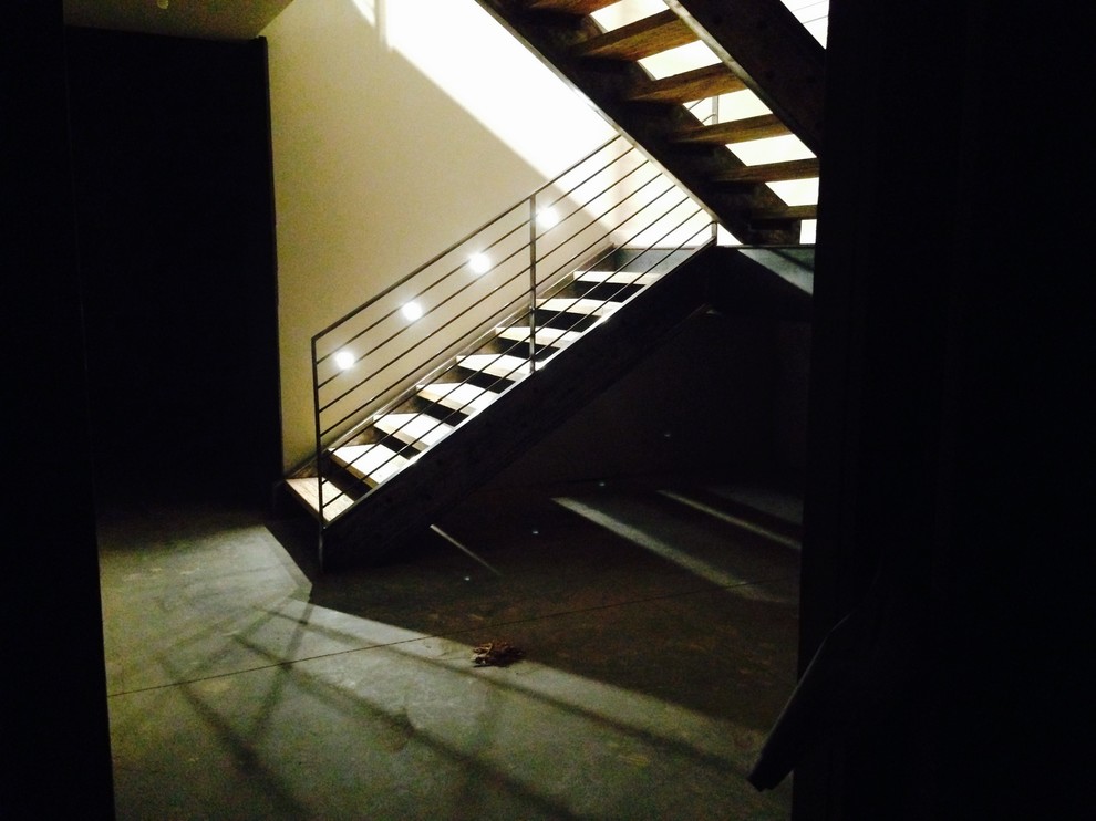 Cette image montre un grand escalier sans contremarche minimaliste en U avec des marches en bois.