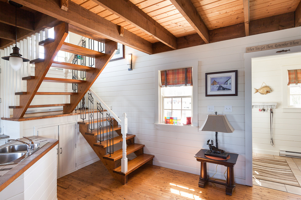 This is an example of a nautical wood u-shaped staircase in Other with open risers and under stair storage.