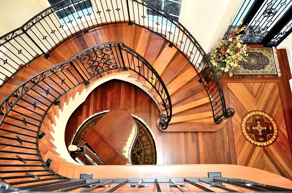 Photo of a large mediterranean wood spiral metal railing staircase in Miami with wood risers.