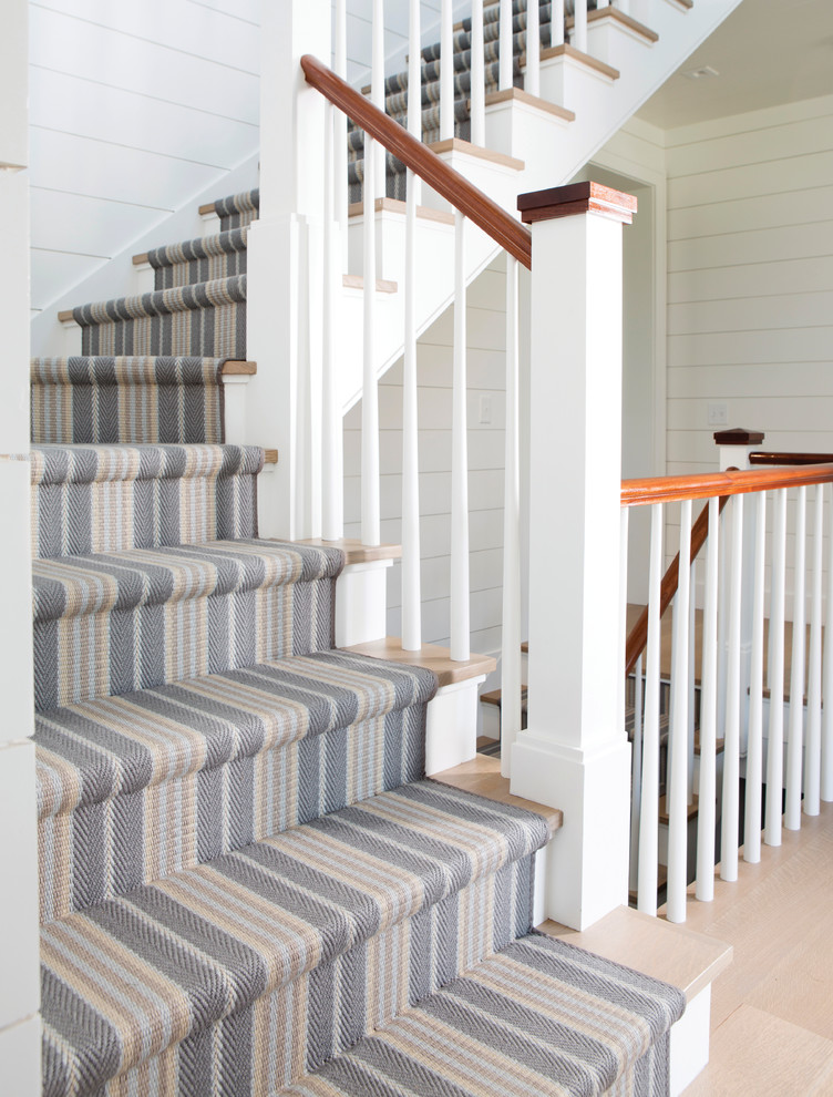На фото: угловая лестница среднего размера в морском стиле с деревянными ступенями, крашенными деревянными подступенками и деревянными перилами с