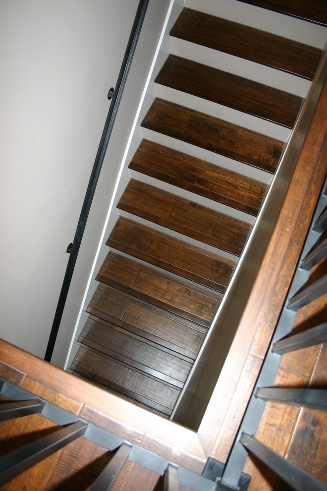 オースティンにある中くらいなカントリー風のおしゃれなかね折れ階段 (フローリングの蹴込み板、金属の手すり) の写真