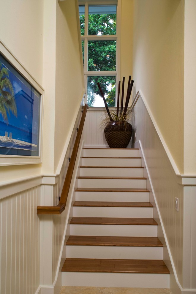 Ejemplo de escalera tropical con escalones de madera y contrahuellas de madera pintada
