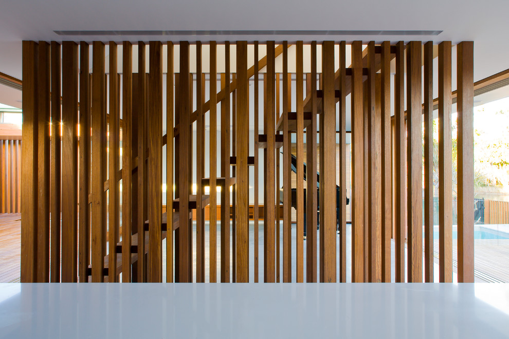 На фото: лестница на больцах, среднего размера в современном стиле с деревянными ступенями и деревянными перилами без подступенок