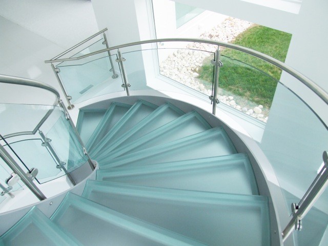 Ejemplo de escalera curva minimalista grande con escalones de vidrio