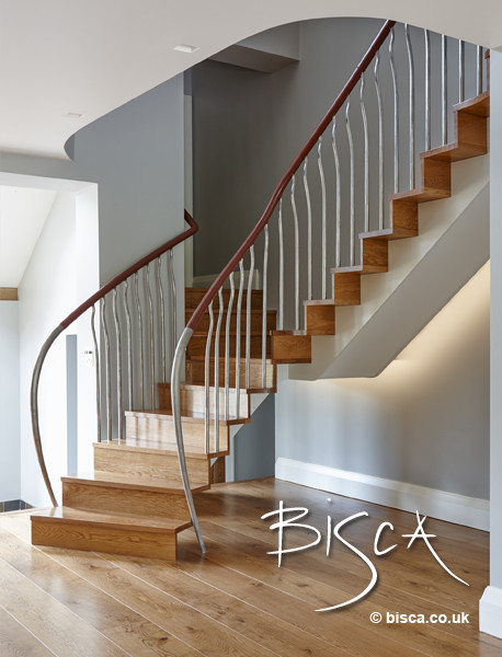 Mid-sized minimalist wooden curved staircase photo in London with wooden risers