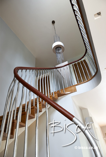 Mid-sized minimalist wooden curved staircase photo in London with wooden risers