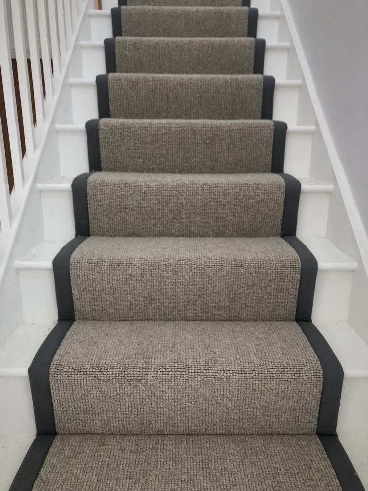 This is an example of a modern carpeted wood railing staircase in Hertfordshire with carpeted risers.