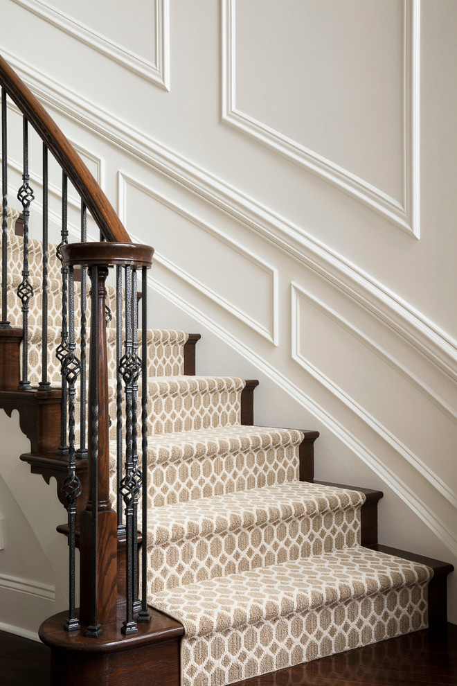 Идея дизайна: большая изогнутая лестница в стиле неоклассика (современная классика) с ступенями с ковровым покрытием, ковровыми подступенками и перилами из смешанных материалов