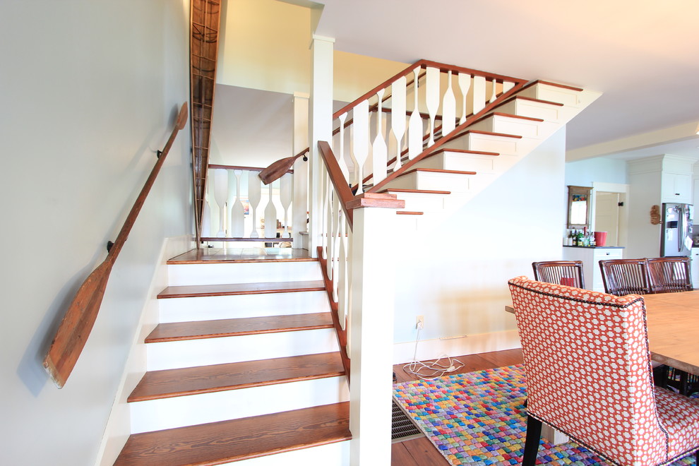This is an example of a large beach style wood l-shaped wood railing staircase in Other with painted wood risers.