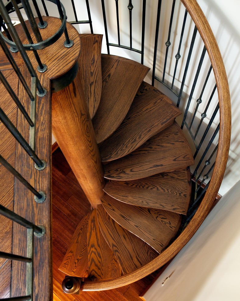 Imagen de escalera de caracol ecléctica grande con escalones de madera y contrahuellas de madera