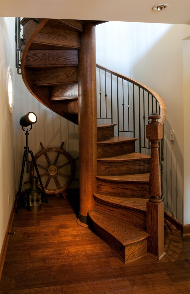 На фото: большая винтовая деревянная лестница в стиле фьюжн с деревянными ступенями