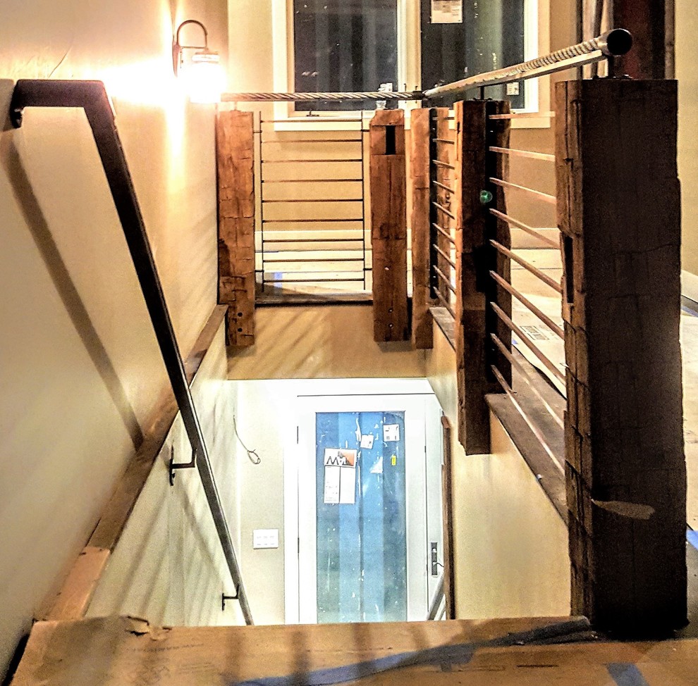 デンバーにあるラグジュアリーな広いラスティックスタイルのおしゃれな直階段 (木の蹴込み板、混合材の手すり) の写真