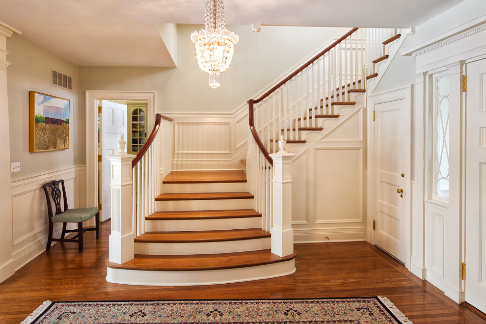 This is an example of an expansive classic wood u-shaped wood railing staircase in New York with wood risers.