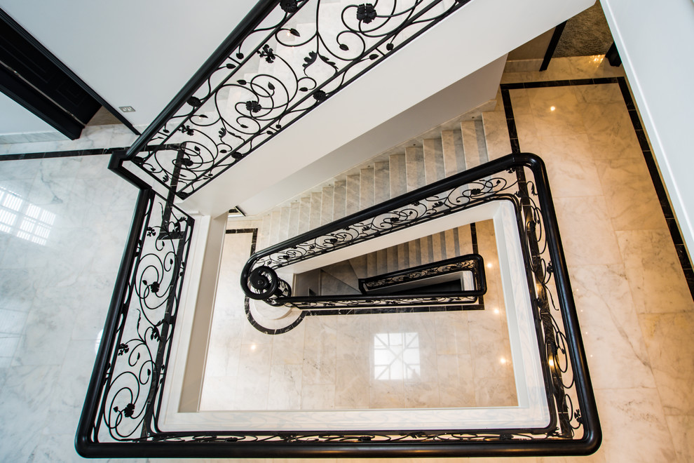 Ejemplo de escalera recta contemporánea grande con escalones de mármol, contrahuellas de mármol y barandilla de metal