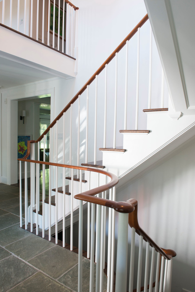 Diseño de escalera curva de estilo de casa de campo de tamaño medio con escalones de madera, contrahuellas de madera y barandilla de madera