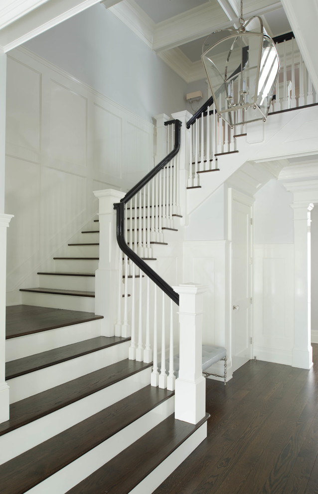 На фото: большая угловая лестница в викторианском стиле с деревянными ступенями и крашенными деревянными подступенками