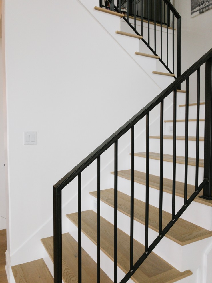 Imagen de escalera en U moderna con escalones de madera pintada, contrahuellas de madera y barandilla de metal