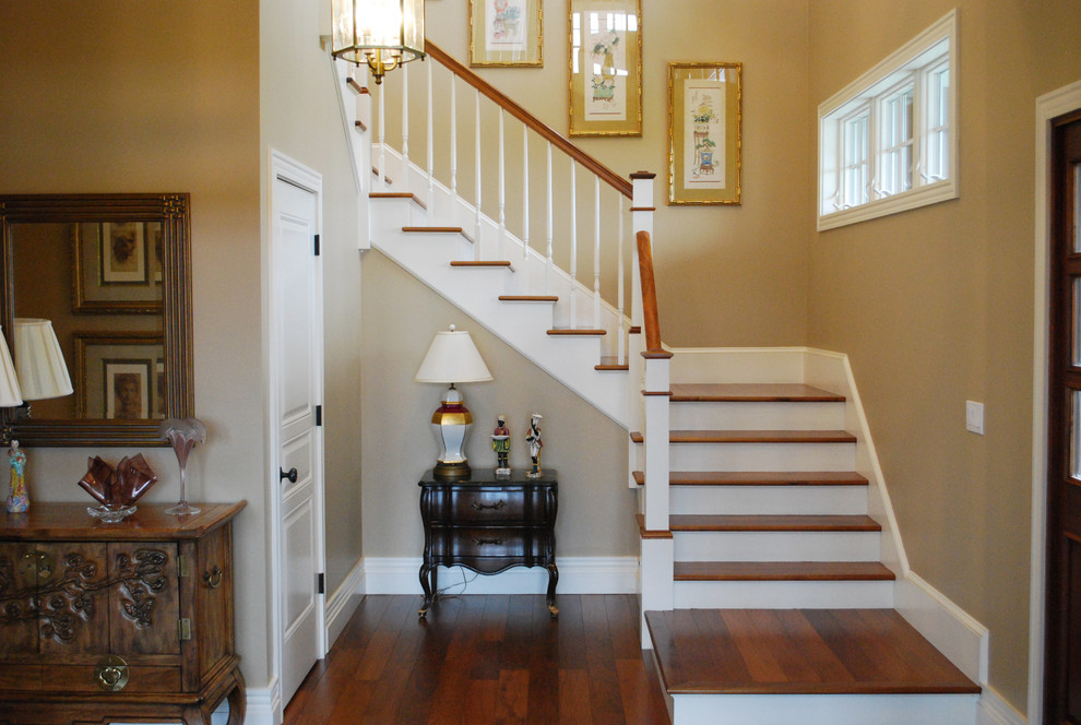 Photo of a large wood l-shaped wood railing staircase in Providence with painted wood risers and feature lighting.