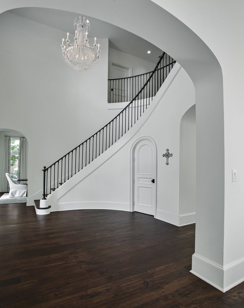 Diseño de escalera curva tradicional grande con escalones de madera, contrahuellas de madera pintada y barandilla de metal