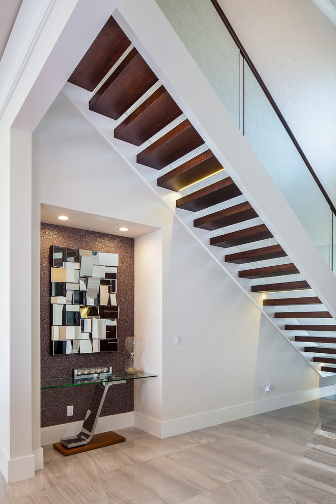 Cette image montre un grand escalier sans contremarche minimaliste en L avec des marches en bois et un garde-corps en verre.