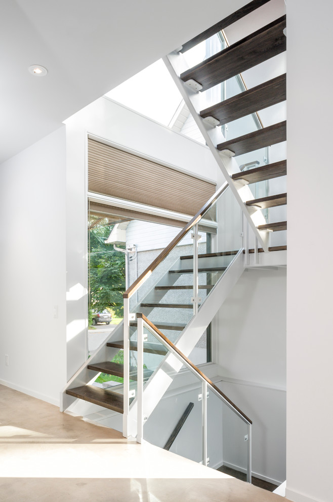 Cette image montre un escalier sans contremarche design avec un garde-corps en verre et palier.